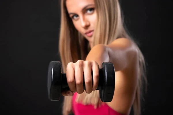 Joven mujer rubia deportiva haciendo levantamiento de pesas sobre blac aislado — Foto de Stock