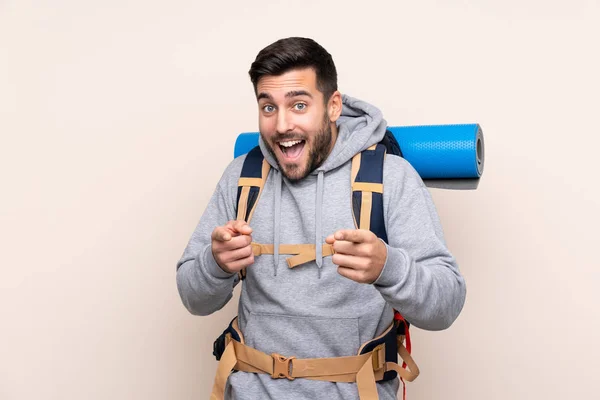 Junger Bergsteiger Mit Großem Rucksack Über Isoliertem Hintergrund Zeigt Mit — Stockfoto