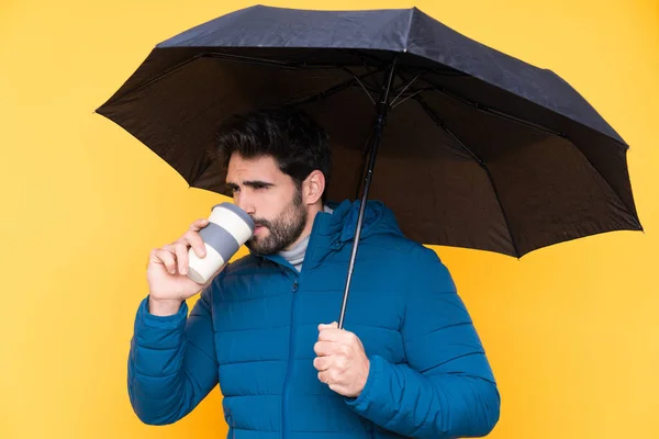 Homme tenant un parapluie sur fond jaune isolé — Photo