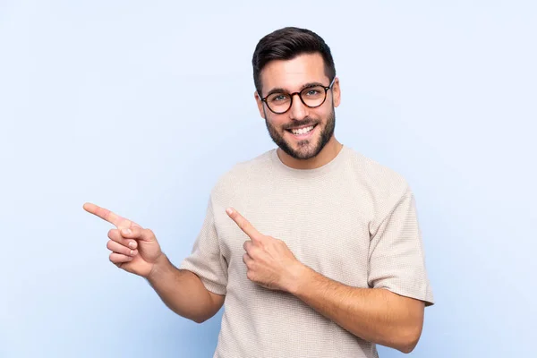 Jonge Knappe Man Met Baard Geïsoleerde Blauwe Achtergrond Wijzende Vinger — Stockfoto