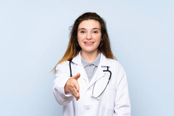 Junge Brünette Mädchen Über Isolierten Blauen Hintergrund Mit Doktorkleid Und — Stockfoto