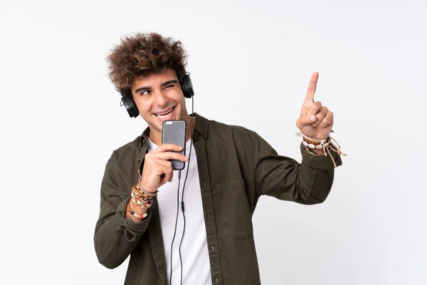 Joven hombre guapo escuchando música con un móvil sobre w aislado —  Fotos de Stock