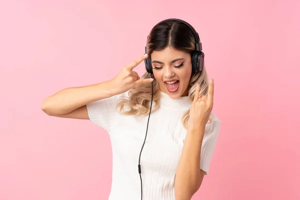 Chica Adolescente Sobre Fondo Rosa Aislado Usando Móvil Con Auriculares —  Fotos de Stock