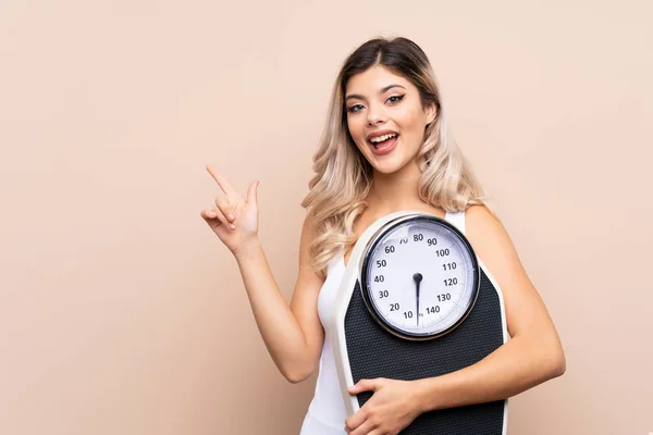 Teenager girl with weighing machine over isolated background with weighing machine