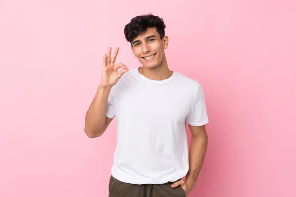 Молодой Аргентинский Мужчина Изолированном Розовом Фоне Показывает Знак Пальцами — стоковое фото