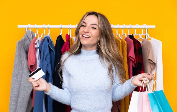 Giovane donna in un negozio di abbigliamento in possesso di una carta di credito e con s — Foto Stock