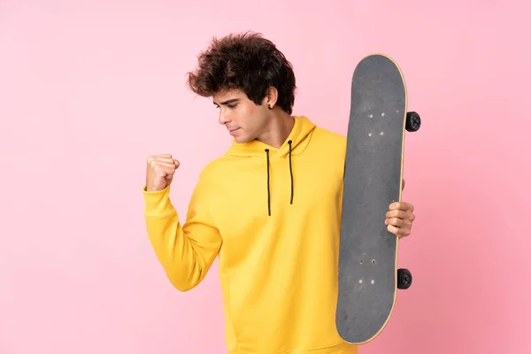若いですCaucasian男上の隔離されたピンクの背景とともにスケートと作る勝利ジェスチャー — ストック写真