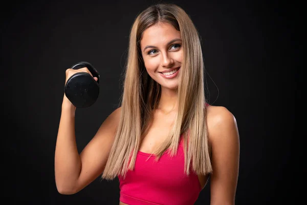 Joven mujer rubia deporte haciendo levantamiento de pesas sobre fondo negro aislado —  Fotos de Stock
