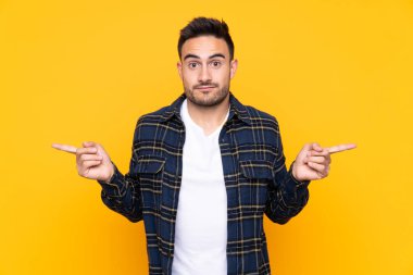 Izole sarı arka plan üzerinde genç yakışıklı adam şüpheleri olan laterals işaret