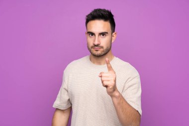 Young handsome man over isolated purple background frustrated and pointing to the front