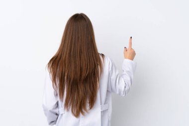 Young woman over isolated background wearing a doctor gown and pointing back