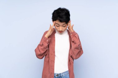 Young Asian girl over isolated blue background with headache