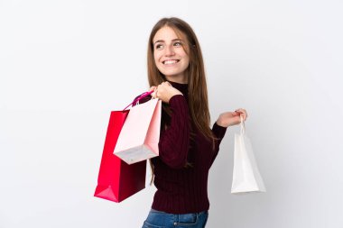 Soyutlanmış beyaz arka planda genç bir kadın alışveriş torbaları tutuyor ve gülümsüyor.