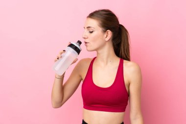 Spor su şişesiyle izole edilmiş pembe arka planı olan genç bir kadın.