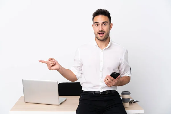 Joven Hombre Negocios Con Teléfono Móvil Lugar Trabajo Sorprendido Señalando —  Fotos de Stock