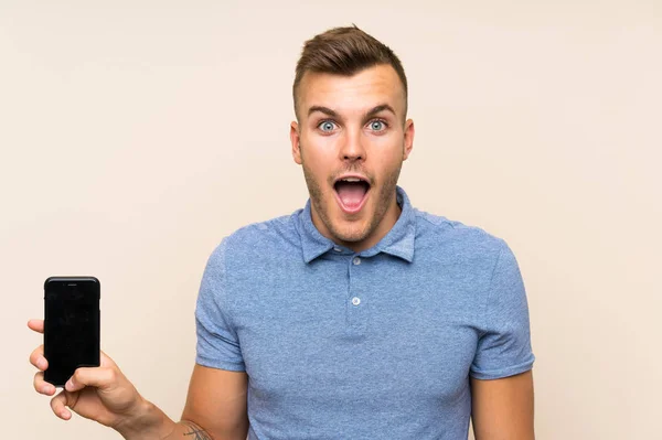 Young Blonde Man Using Mobile Phone Surprise Shocked Facial Expression — Stock Photo, Image