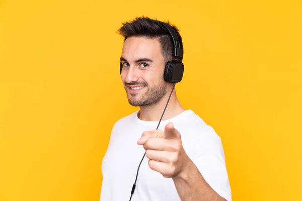 Young Man Yellow Background Listening Music Pointing Front — 스톡 사진