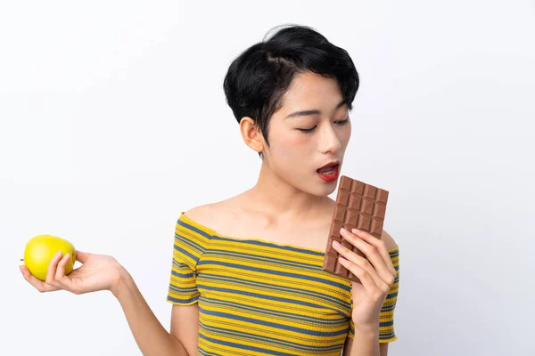 Mladá Asijská Dívka Brát Čokoládovou Tabletu Jedné Ruce Jablko Druhé — Stock fotografie