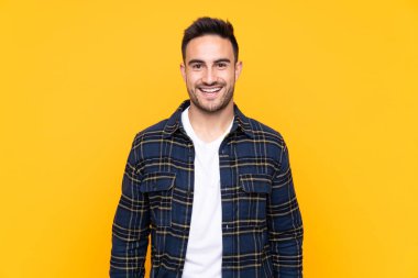 Sürpriz yüz ifadesi ile izole sarı arka plan üzerinde genç yakışıklı adam