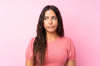 Izole pembe arka plan ayakta ve yan bakarak genç kadın