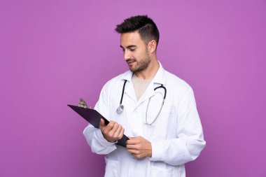 Doktor önlüğü giyen ve elinde dosya tutan genç bir adam.