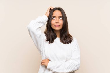 Izole arka plan üzerinde beyaz kazak ile genç esmer kadın şüpheler ve yüz ifadesi karıştırarak sahip