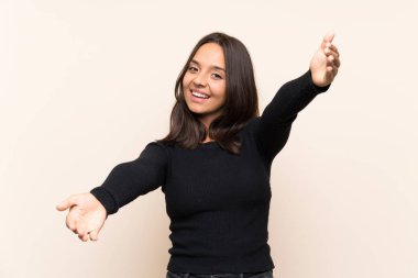 İzole edilmiş arka planda beyaz kazaklı genç esmer kadın sunar ve davet eder.