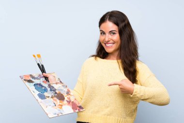 Izole mavi arka plan üzerinde genç sanatçı kadın ve işaret