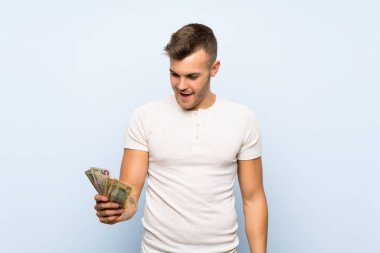Izole mavi arka plan üzerinde genç yakışıklı sarışın adam çok para alarak