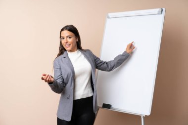 Beyaz tahtada sunum yapan genç bir kadın beyaz tahtada sunum yapıyor.