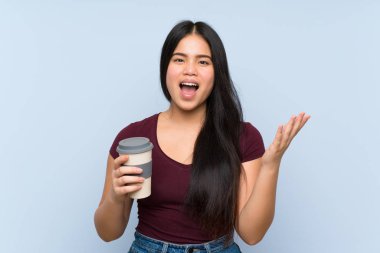 Genç Asyalı kız elinde şok olmuş bir yüz ifadesiyle kahve tutuyor.