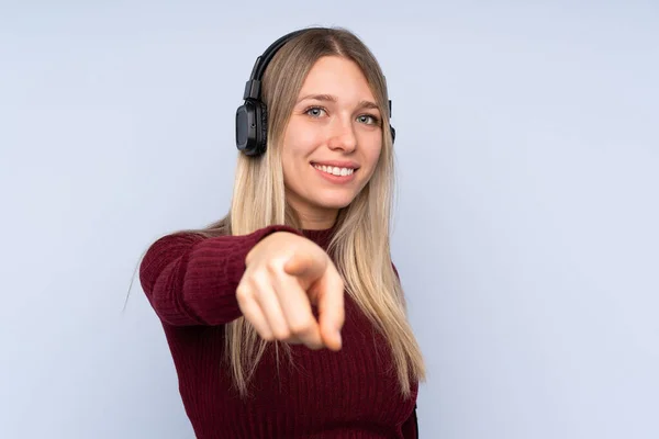 Mujer Rubia Joven Sobre Fondo Azul Aislado Escuchando Música Señalando —  Fotos de Stock