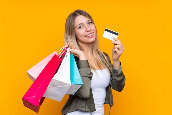Young Blonde Woman Isolated Yellow Background Holding Shopping Bags Credit — 스톡 사진