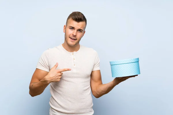 Ung Stilig Blondin Man Över Isolerad Blå Bakgrund Holding Gift — Stockfoto