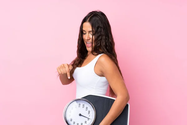 Young Woman Isolated Pink Background Holding Weighing Machine Pointing — 스톡 사진