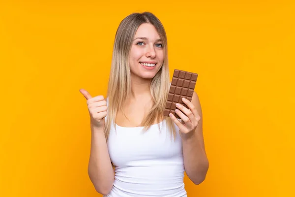 Mladá Blondýna Žena Přes Izolované Modré Pozadí Čokoládovou Tabletu Palcem — Stock fotografie