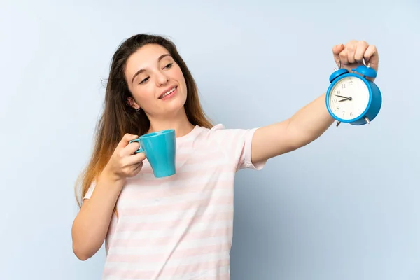 Jovem morena segurando uma xícara de café e relógio vintage sobre fundo isolado — Fotografia de Stock