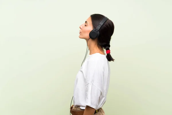 Mujer Joven Sobre Fondo Verde Aislado Escuchando Música Con Auriculares —  Fotos de Stock