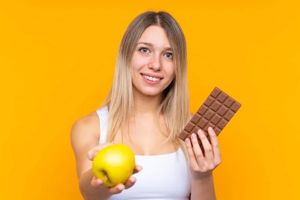 Joven Rubia Sobre Fondo Azul Aislado Tomando Una Tableta Chocolate — Foto de Stock