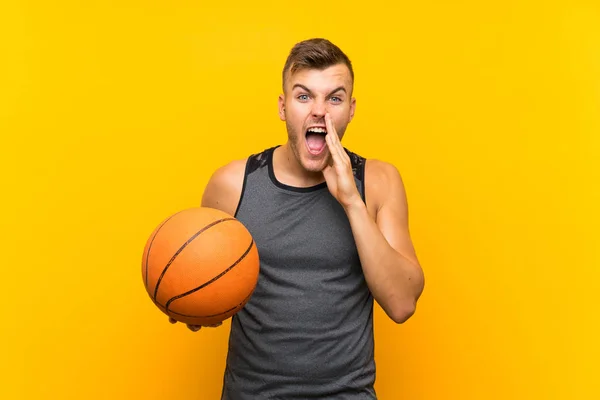 Young Handsome Blonde Man Holding Basket Ball Isolated Yellow Background — 스톡 사진