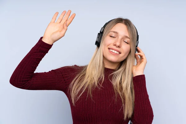 Νεαρή Ξανθιά Γυναίκα Πάνω Από Απομονωμένο Μπλε Φόντο Ακούγοντας Μουσική — Φωτογραφία Αρχείου