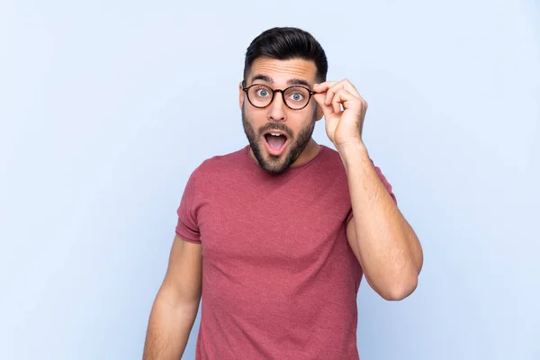 Mladý Pohledný Muž Vousem Přes Izolované Modré Pozadí Brýlemi Překvapený — Stock fotografie