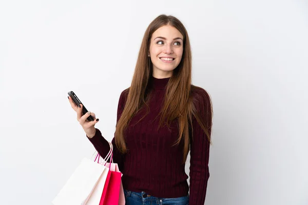 Ung Kvinna Över Isolerad Vit Bakgrund Med Shoppingväskor Och Mobiltelefon — Stockfoto