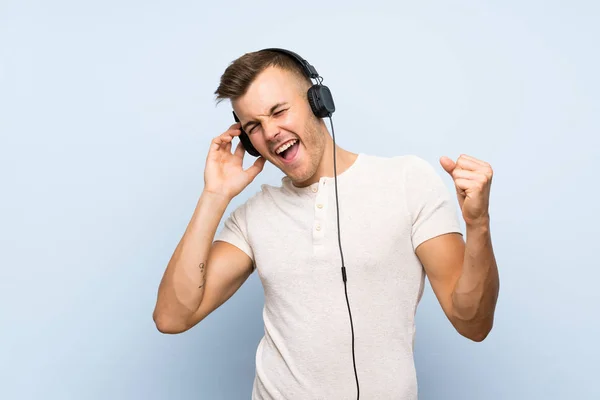 Mladý Pohledný Blonďák Přes Izolované Modré Pozadí Poslouchá Hudbu Sluchátky — Stock fotografie