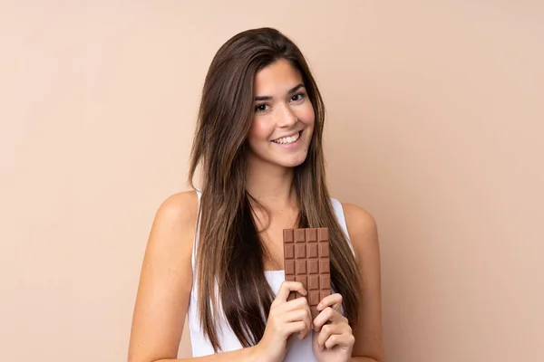 Teenager Dívka Přes Izolované Pozadí Čokoládovou Tabletu Šťastný — Stock fotografie