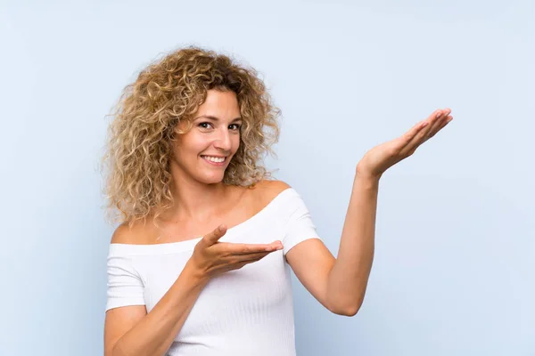 Jonge Blonde Vrouw Met Krullend Haar Geïsoleerde Blauwe Achtergrond Reikende — Stockfoto