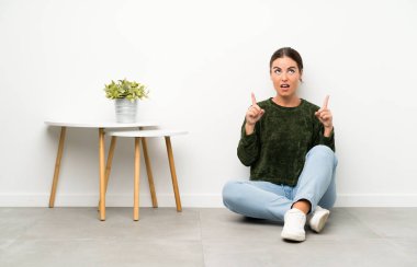 Yerde oturan genç bayan işaret parmağıyla işaret etmek harika bir fikir.