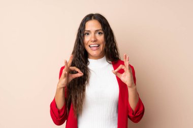 İzole edilmiş arka planda genç bir kadın parmaklarıyla iyi bir işaret gösteriyor.