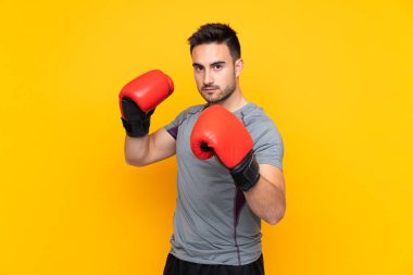 İzole edilmiş sarı duvardaki boks eldivenli sporcu.