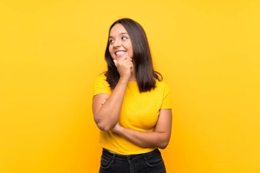 Genç esmer kız soyutlanmış arka planda yan tarafa bakıyor.